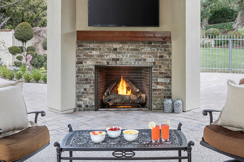 A brick fireplace in a non-connected wall on a back patio with snacks on a table