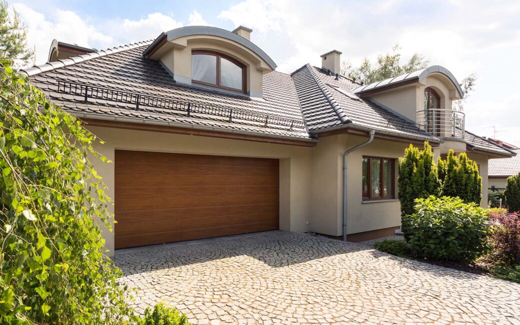 Detached family house exterior with cobblestone driveway to the garage and spruce garden
