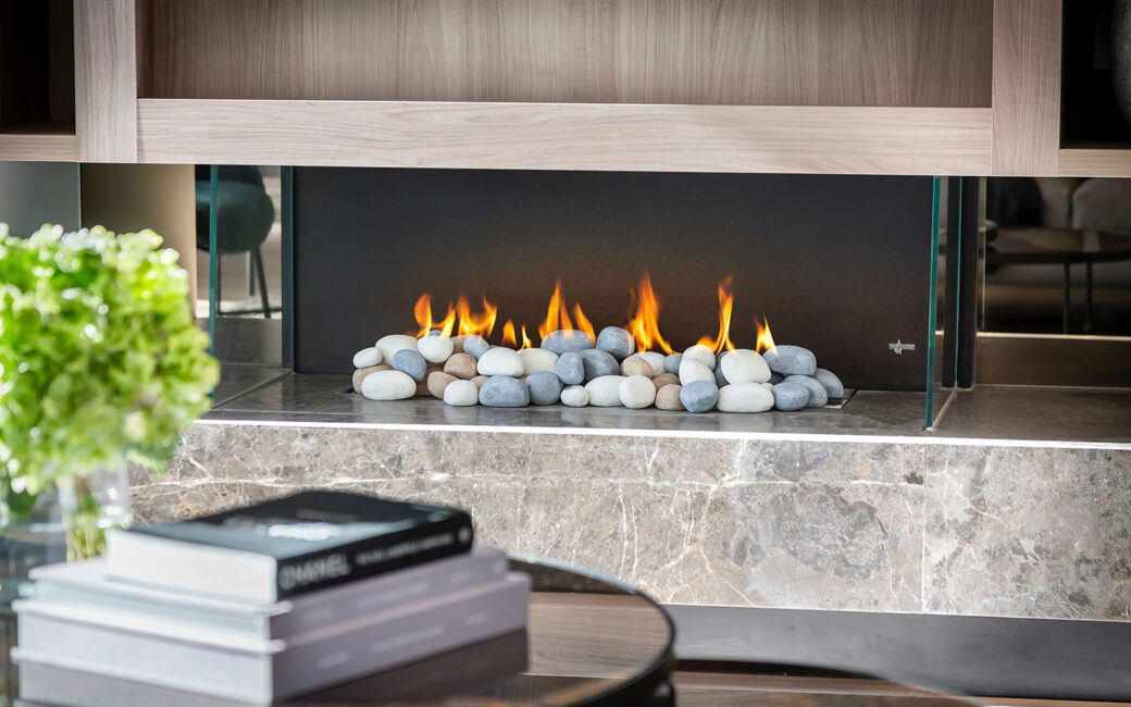 A gas fireplace with stones in a chic living room