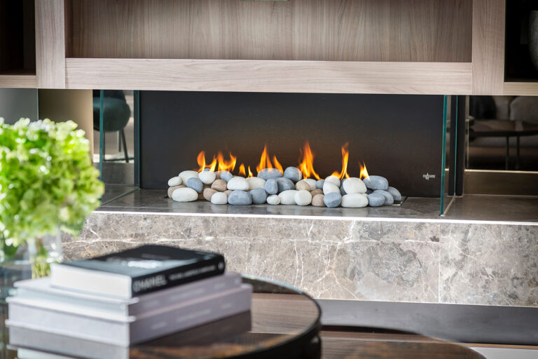 A gas fireplace with stones in a chic living room