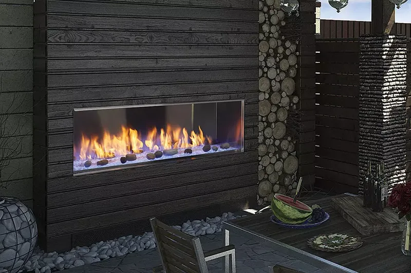 Outdoor modern wood log fireplace burning blue and red flame, with an outdoor table for sitting